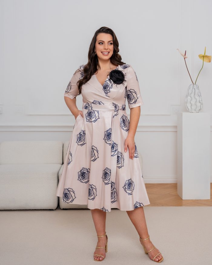 Elegancka sukienka plus size w pudrowym odcieniu z granatowymi różami i czarnym kwiatem.