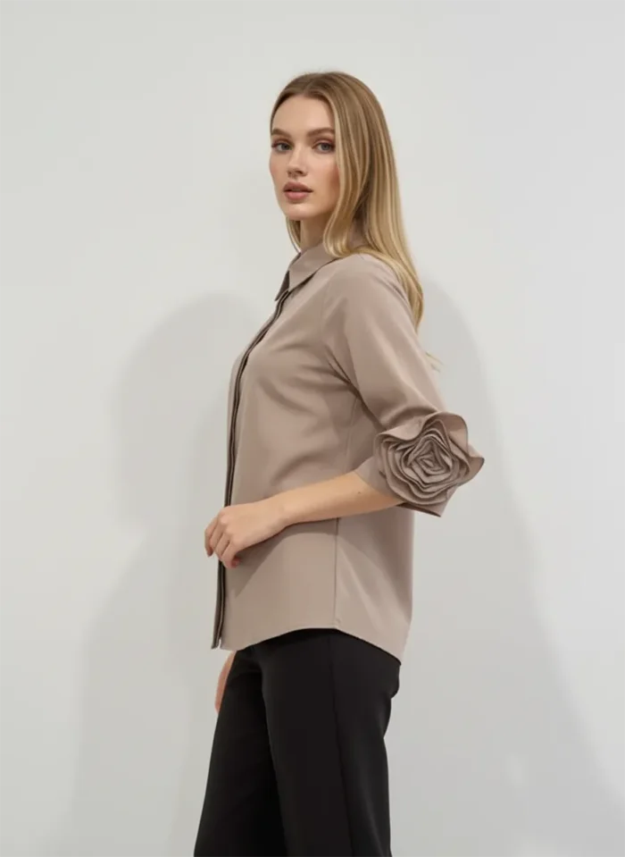 Elegancka beżowa bluzka damska z kołnierzykiem i ozdobnym kwiatem na rękawie, na wyjście.